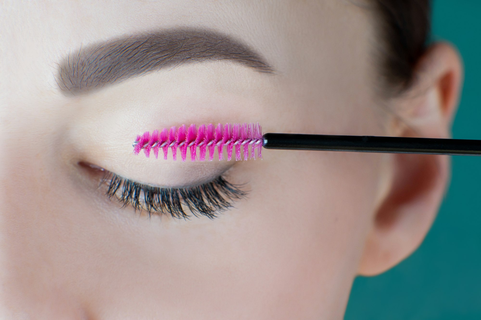 Closed eye with long eyelashes, black eyeliner, perfect skin eyebrow of unrecognizable young woman