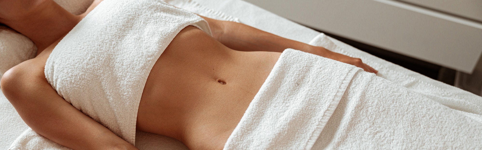 Slim young woman lying on massage table in spa salon